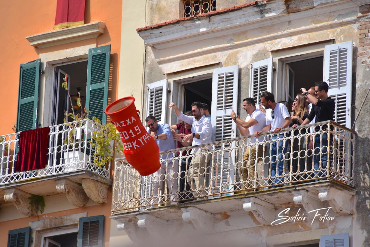 People throwing a large red clay pot from a balcony during the Botides tradition in Corfu