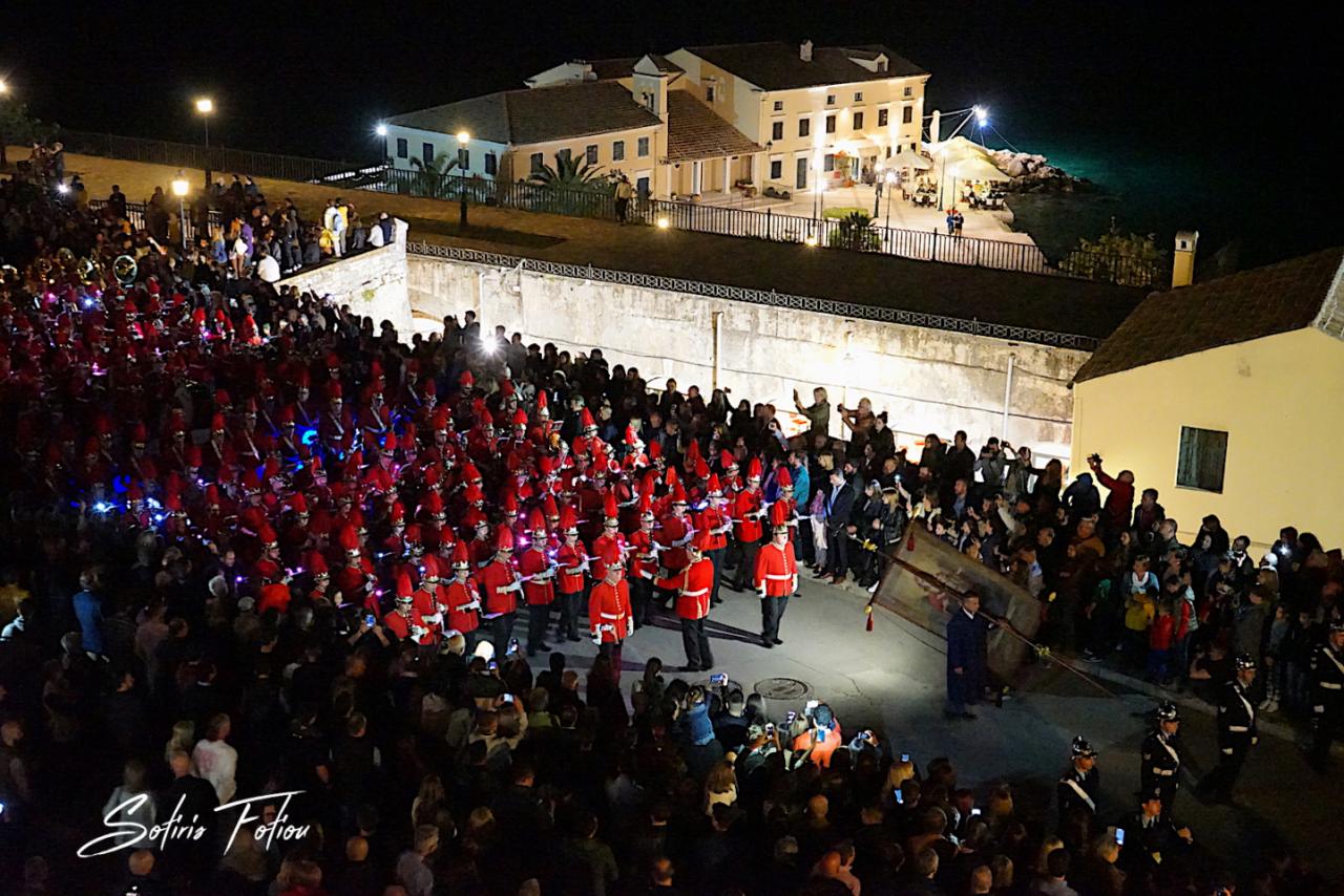 Corfu's philharmonic band marching in red uniforms at night during an Easter procession